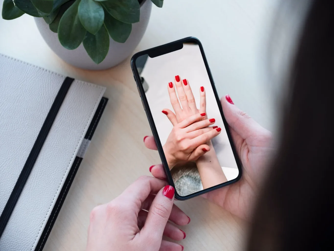 Móvil con una foto de una manicura con uñas rojas