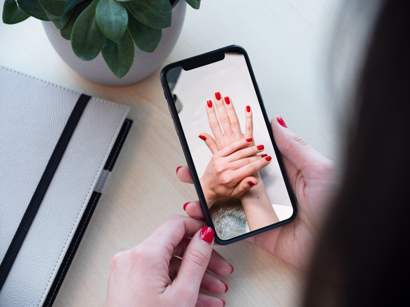 Móvil con una foto de una manicura con uñas rojas
